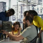 Software developers discussing code on multiple monitors in modern office