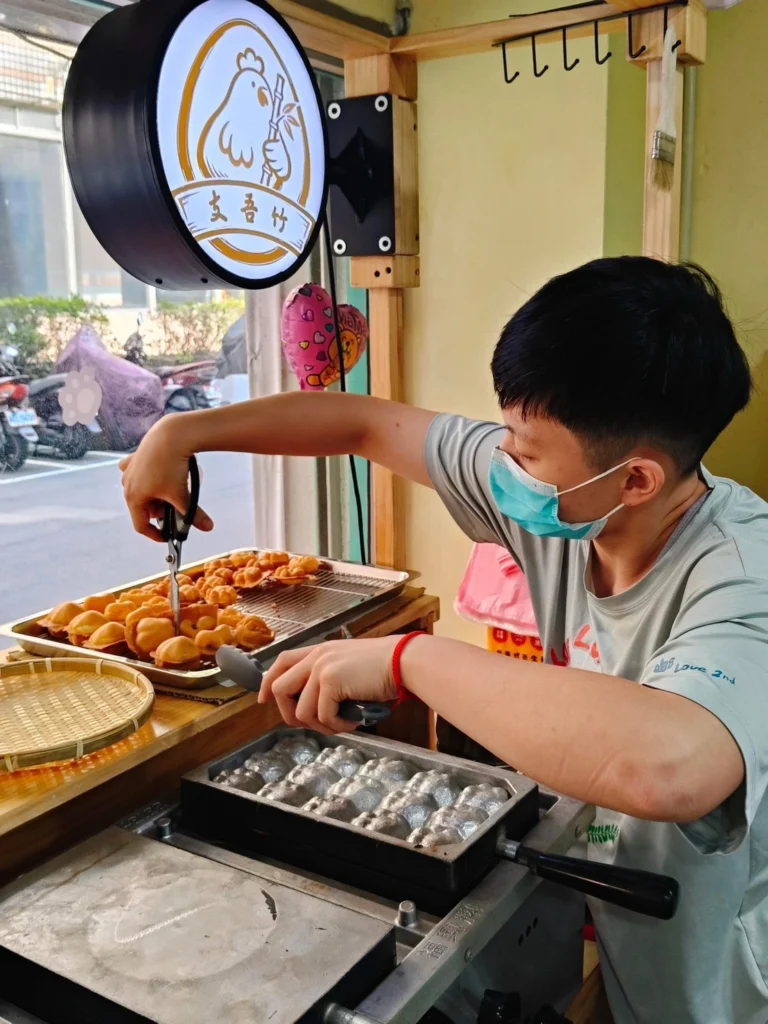 店主於攤位現場製作雞蛋糕，從烤模操作、翻烤到成品整理，皆希望維持穩定口感與品質。/圖片來源 : 支吾竹雞蛋糕